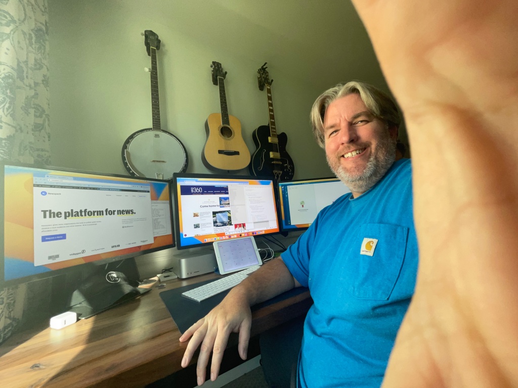 Dan at his desk, making the universal "talk to the hand" gesture ... but with a big old grin on his face.